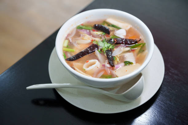 Tom yum goong, or spicy shrimp soup, served hot and sour in a bowl on a wooden table background