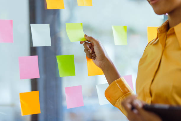 istock Young African American stylish woman working on project plan using sticky papers notes on glass wall. 2158809683