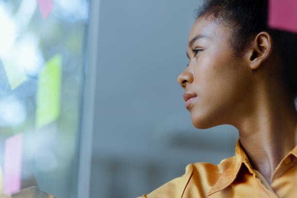 istock Young African American stylish woman working on project plan using sticky papers notes on glass wall. 2158809712