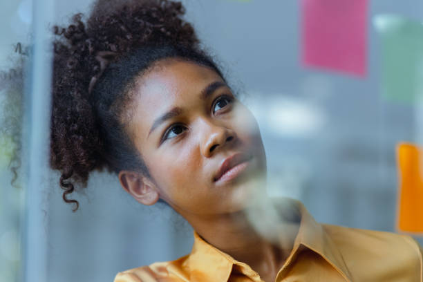 istock Young African American stylish woman working on project plan using sticky papers notes on glass wall. 2158809717