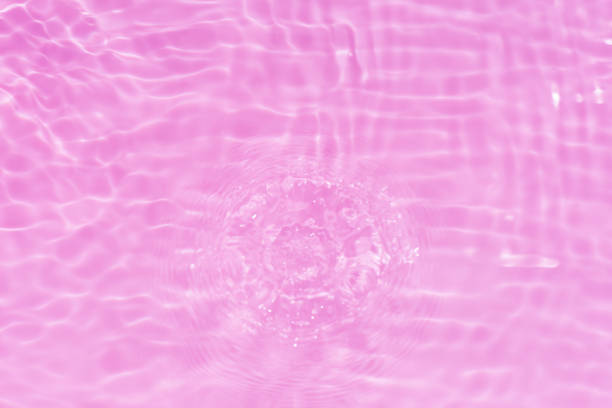 Blue water with ripples on the surface. Defocus blurred transparent blue colored clear calm water surface texture with splashes and bubbles. Water waves with shining pattern texture background.