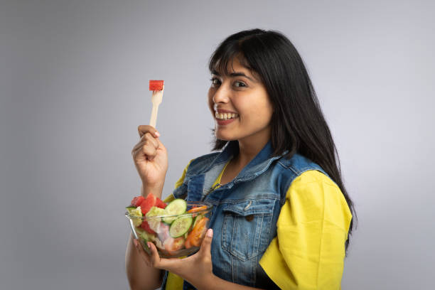 istock Woman smiling and eating fruit salad on gray background 2158811596