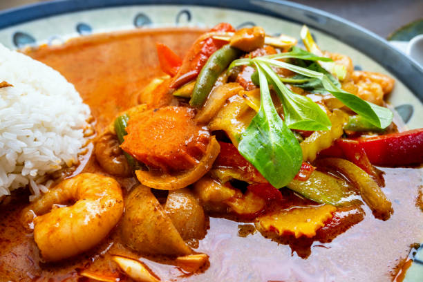 Detail of spicy red curry sauce with vegetable and rice. Asian meal.