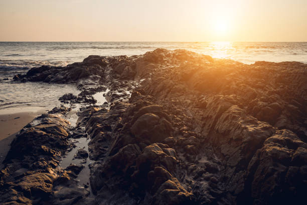 A large rocks surrounded by waves of the ocean.