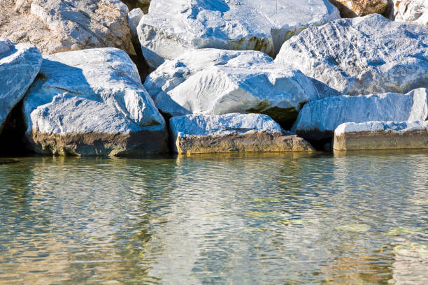 Stone breakwater rocks are reflected in the water.