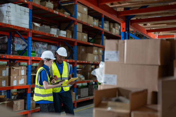 istock Professional female and man warehouse worker with digital tablet talking together and checking stock products in boxes on shelves at warehouse factory store. Logistics, Distribution Center concept. 2158824353