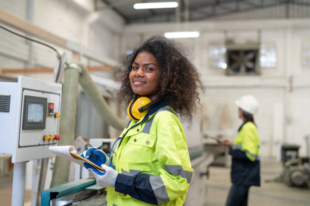 istock African American woman engineer using computer operating CNC machine for cutting wood in furniture factory. Female technical smiling and working maintenance machine for making wooden product. 2158824668