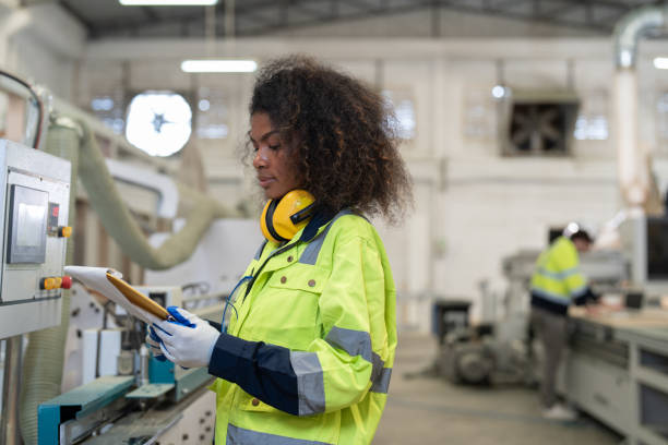 istock African American woman engineer using computer operating CNC machine for cutting wood in furniture factory. Female technical maintenance and programming to machine for making wooden product. 2158825333