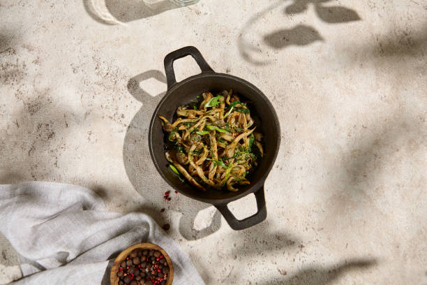istock Sunlit Fried Oyster Mushrooms with Herbs Summer Delicacy in Rustic Pot with Shadows 2158826428