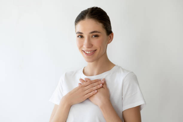 istock Young woman smiling and keeps both palms on chest, looking to the camera. 2158830364