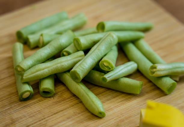 Cutting board with ingredients for preparing green curry with herbs and rice.
