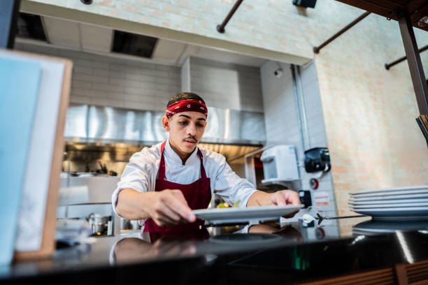 istock Young chef preparing food on a plate at commercial kitchen 2158834949