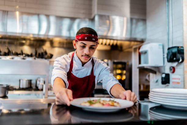 istock Young chef preparing food on a plate at commercial kitchen 2158834988