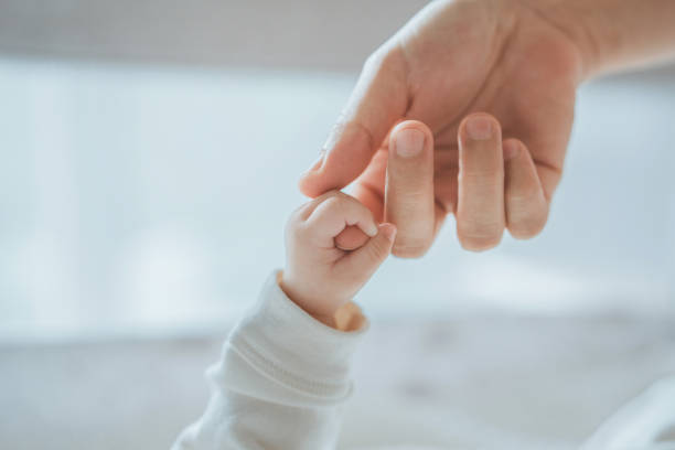 mano pequeña de primer plano del bebé del niño que sostiene la mano de la madre, un recién nacido se aferra al dedo de mamá, papá, amor y relación con el bebé, cuidado y apoyo, soñar y protección - bebé fotografías e imágenes de stock