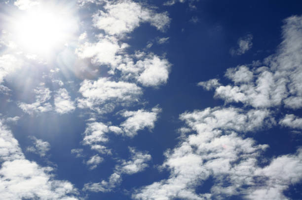 Bright light of the sun on a dark blue sky among the clouds. Dramatic view of the sun.
