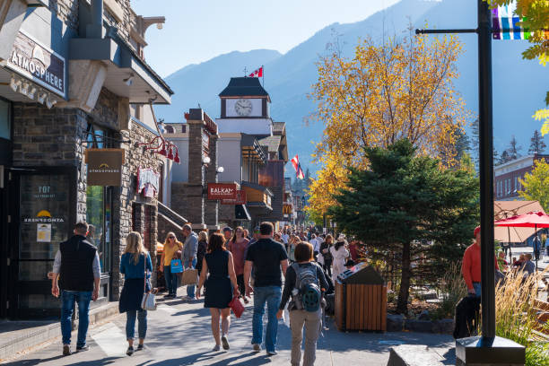 Banff, Alberta, Canada - October 06 2022 : Crowds of people shopping on Banff Avenue in a autumn sunny day.