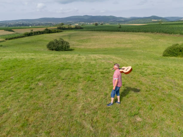 Man with his guitar outside in countryside. Relaxing to improve his mental health