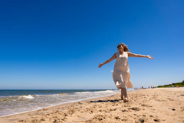 istock Beautiful young woman walking on sunny beach 2158843207
