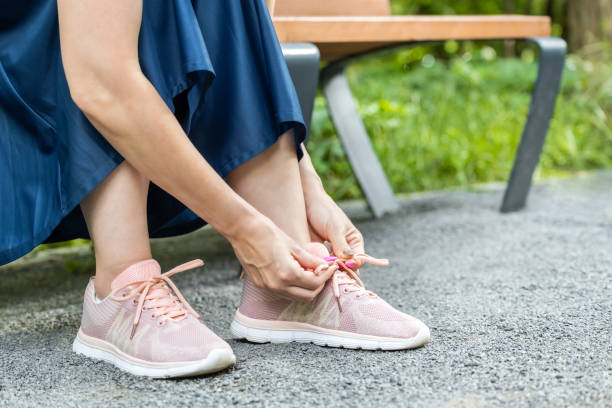 istock woman tying laces on sneakers while sitting on a bench 2158844564
