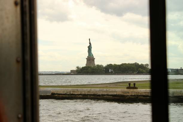 The Statue of Liberty taken from the window of a New York ferry docking at the Ellis Centre Immigration Museum on a cloudy day.