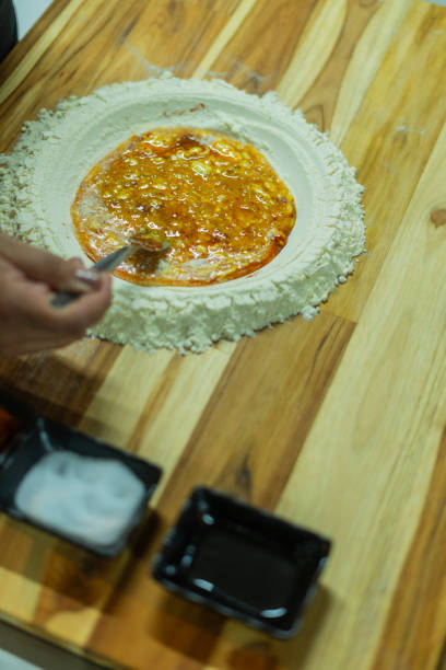 Beautiful young woman in chef hat is mixing batter, looking at camera and smiling while baking in kitchen at home