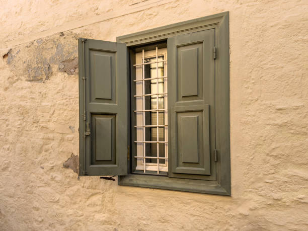 window, opened wooden window blind or shutter on wall with copy space. window of village house or home old painted wooden shutters on pastel colored stone wall background or surface. building exterior
