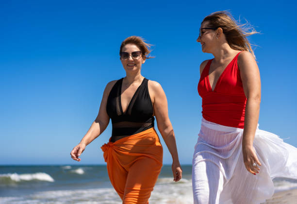 istock Beautiful women walking on sunny beach 2158853580