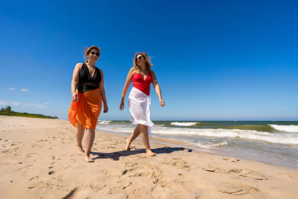 istock Beautiful women walking on sunny beach 2158853599