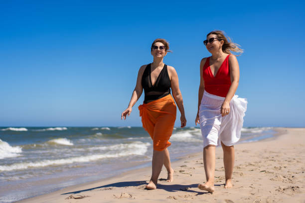 istock Beautiful women walking on sunny beach 2158853627