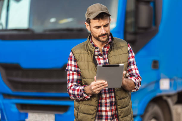 istock Happy confident male driver standing in front on his truck, using his tablet. 2158856649