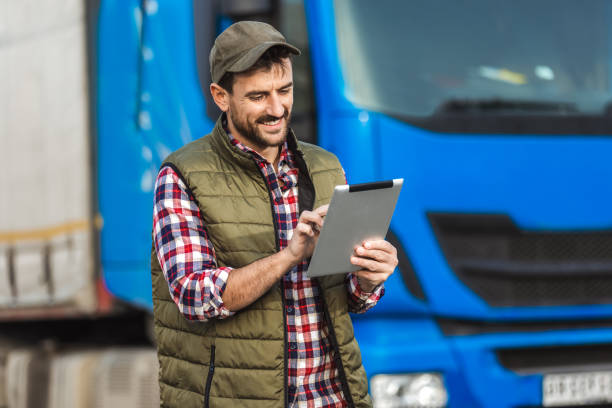 istock Happy confident male driver standing in front on his truck, using his tablet. 2158856668