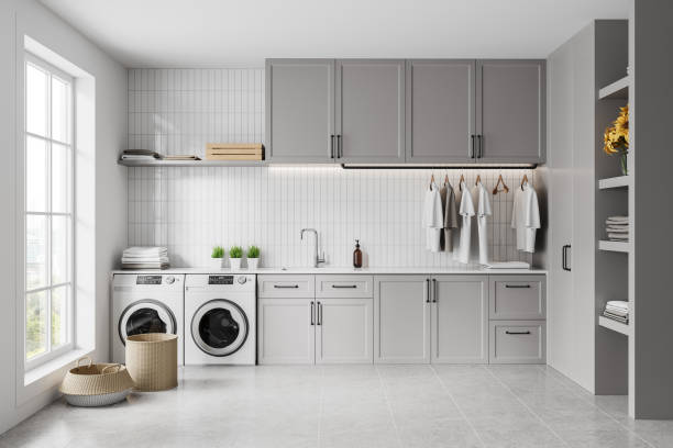 istock Grey home laundry interior with washing cabinet and sink, panoramic window 2158857304