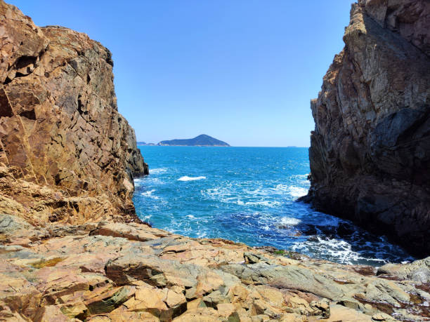 The rocky cliffs on South China sea at the famous Crab Cave in Cape D'Aguilar, or Hok Tsui, a cape on southeastern Hong Kong Island, Hong Kong. The peninsula, where the cape is on its southeastern side, is also known as Cape D'Aguilar. It is named after Major-General George Charles D'Aguilar.