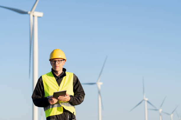 istock Engineer with digital tablet works on a field of wind turbines 2158864453