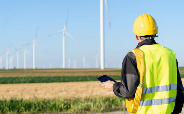 istock Engineer with digital tablet works on a field of wind turbines 2158865617