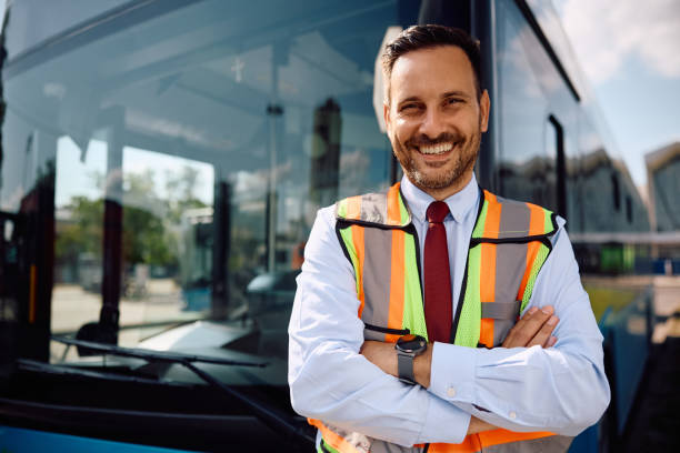 istock Happy driver with crossed arms in front of a bus looking at camera. 2158867270