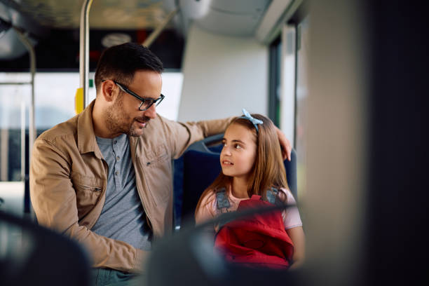 istock Schoolgirl and her father communicating while riding in a bus. 2158867516