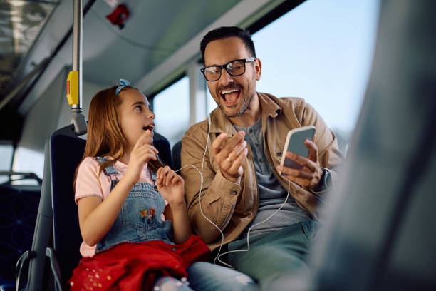 Cheerful father and daughter having fun while commuting by bus.