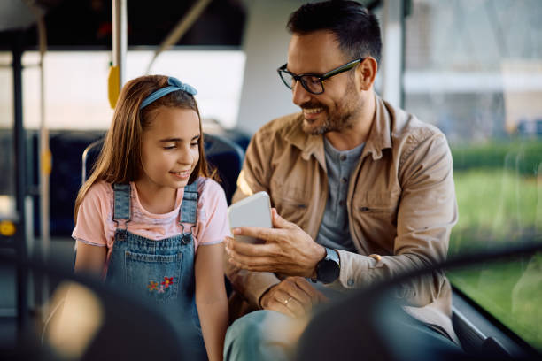 istock Happy father and daughter using cell phone while riding in a bus. 2158867616