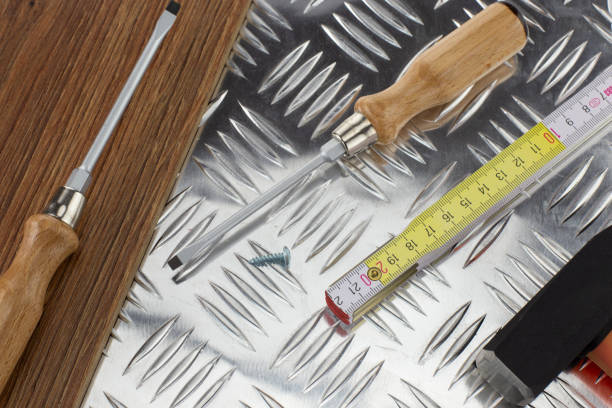 Assorted tools including screwdrivers and tape measure on a metal plate.