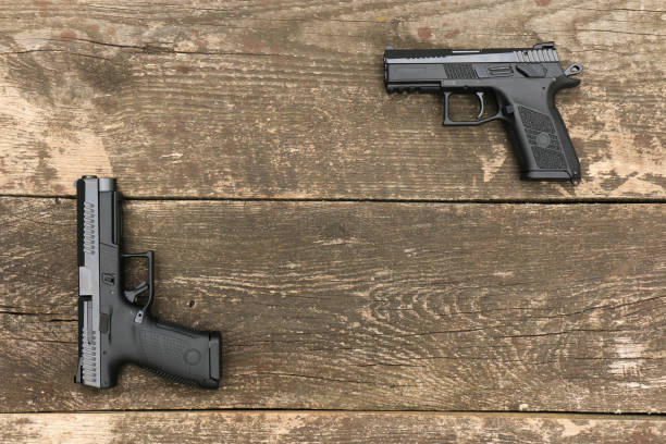 istock Two modern automatic pistols on old boards form a frame with an empty space in the middle 2158871977