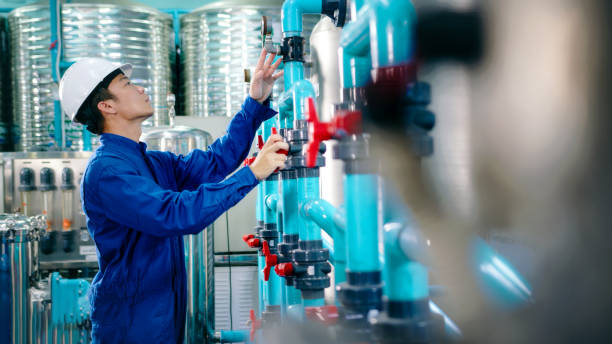 istock Maintenance engineer Worker in a hard hat adjusting valves and examining  pressure gauge on industrial piping in a water treatment facility. water bottling 2158874019