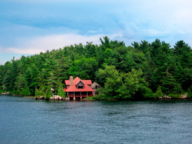 Large wood and stone log home surrounded by a cloudy sky and a lake.