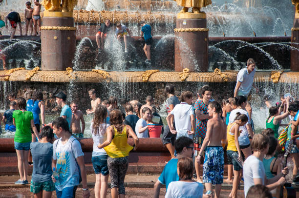 Hot summer day. Mother splashing laughing kids in back yard.Nikon D850