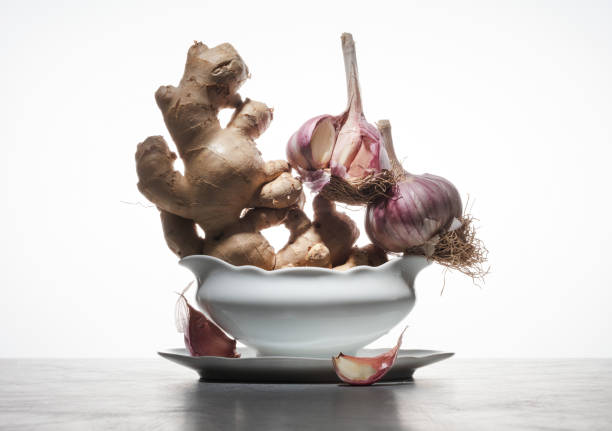 Ginger root and garlic in a bowl white table and background. Healthy Food concept. Selective focus