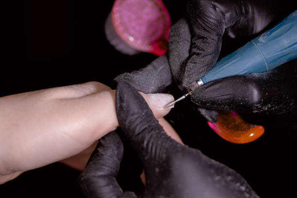 istock Technician in black gloves using tool for precise treatment of client's nail. 2158894288