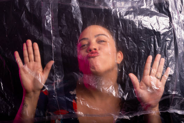 istock Beautiful woman with her hands leaning against transparent plastic 2158898134
