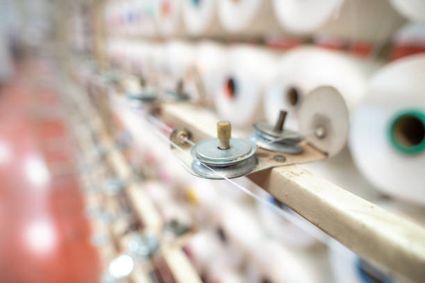 Textile yarn manufacturing, synthetic yarn, polyester and polypropylene production stages, yarn wound as bobbins. warp thread