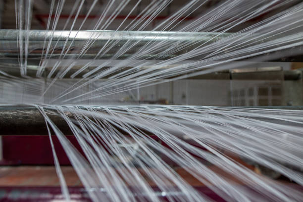 Textile yarn manufacturing, synthetic yarn, polyester and polypropylene production stages, yarn wound as bobbins. warp thread