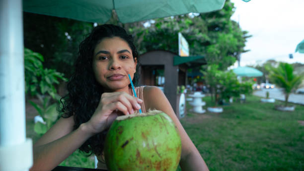 istock middle aged latin woman drinking coconut water 2158903037